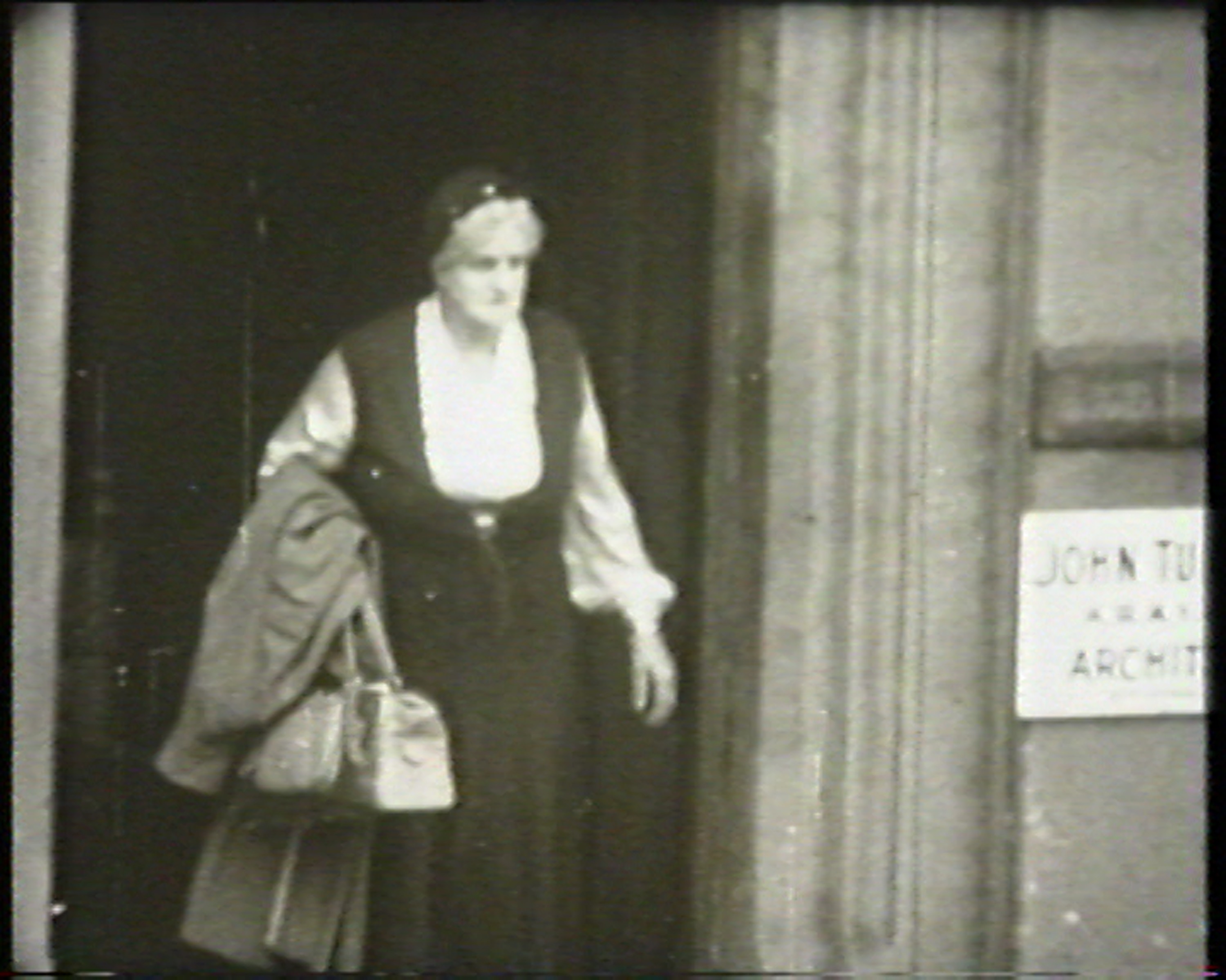 中年妇女的黑白图像走出大楼入口。